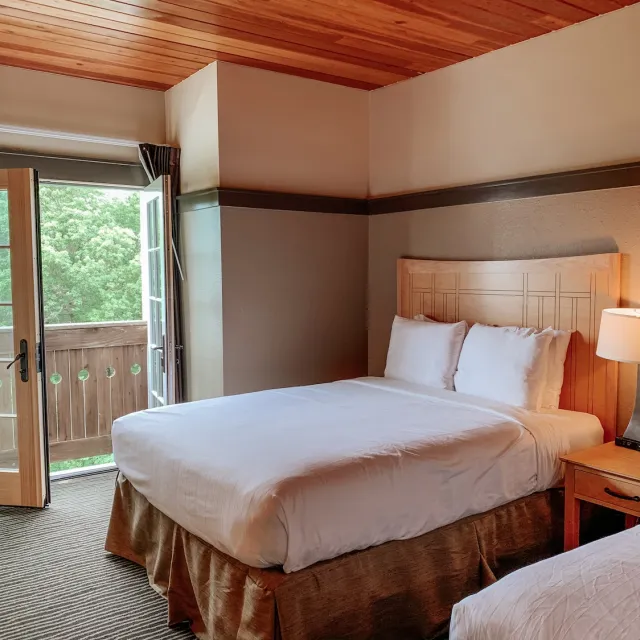 A room featuring two beds and a sliding door, creating a spacious and inviting atmosphere.