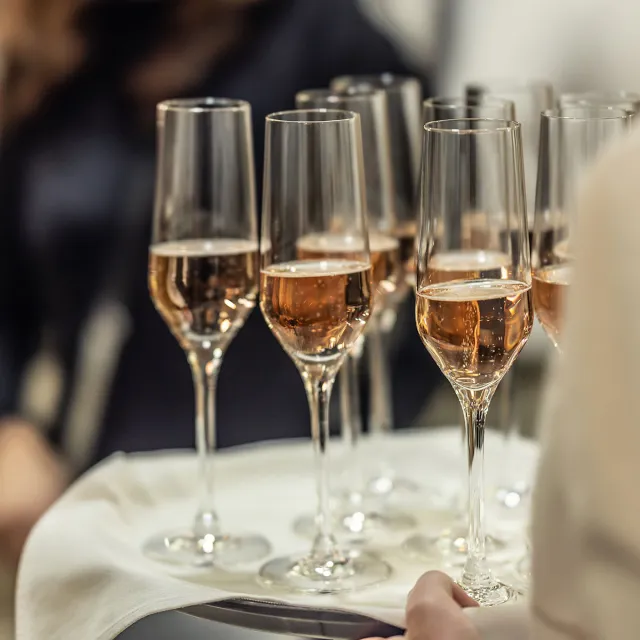 Champagne glasses full of sparkling champagne being carried by waiter