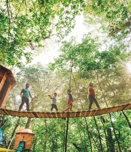 A group of individuals crossing a suspension bridge in a serene woodland setting.