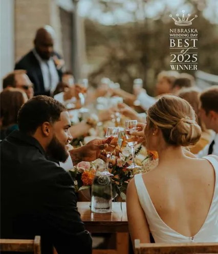 Guests cheer with champagne glasses at a beautifully decorated wedding reception table, surrounded by floral arrangements.
