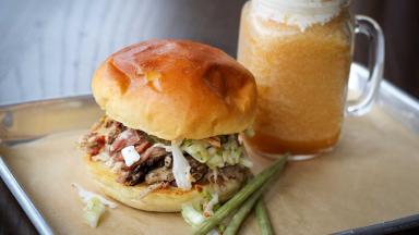  A pulled pork sandwich served alongside a glass of beer.