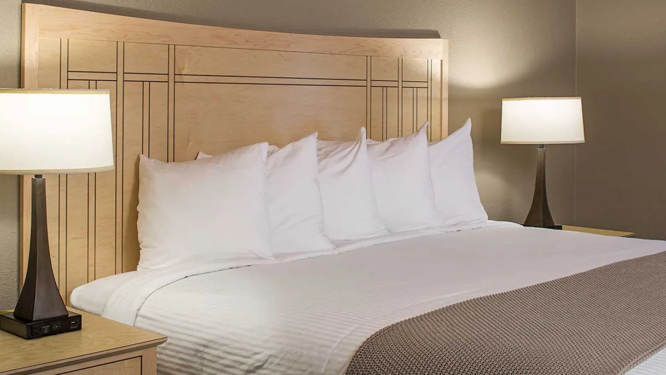 A neatly made bed featuring crisp white sheets and fluffy white pillows.